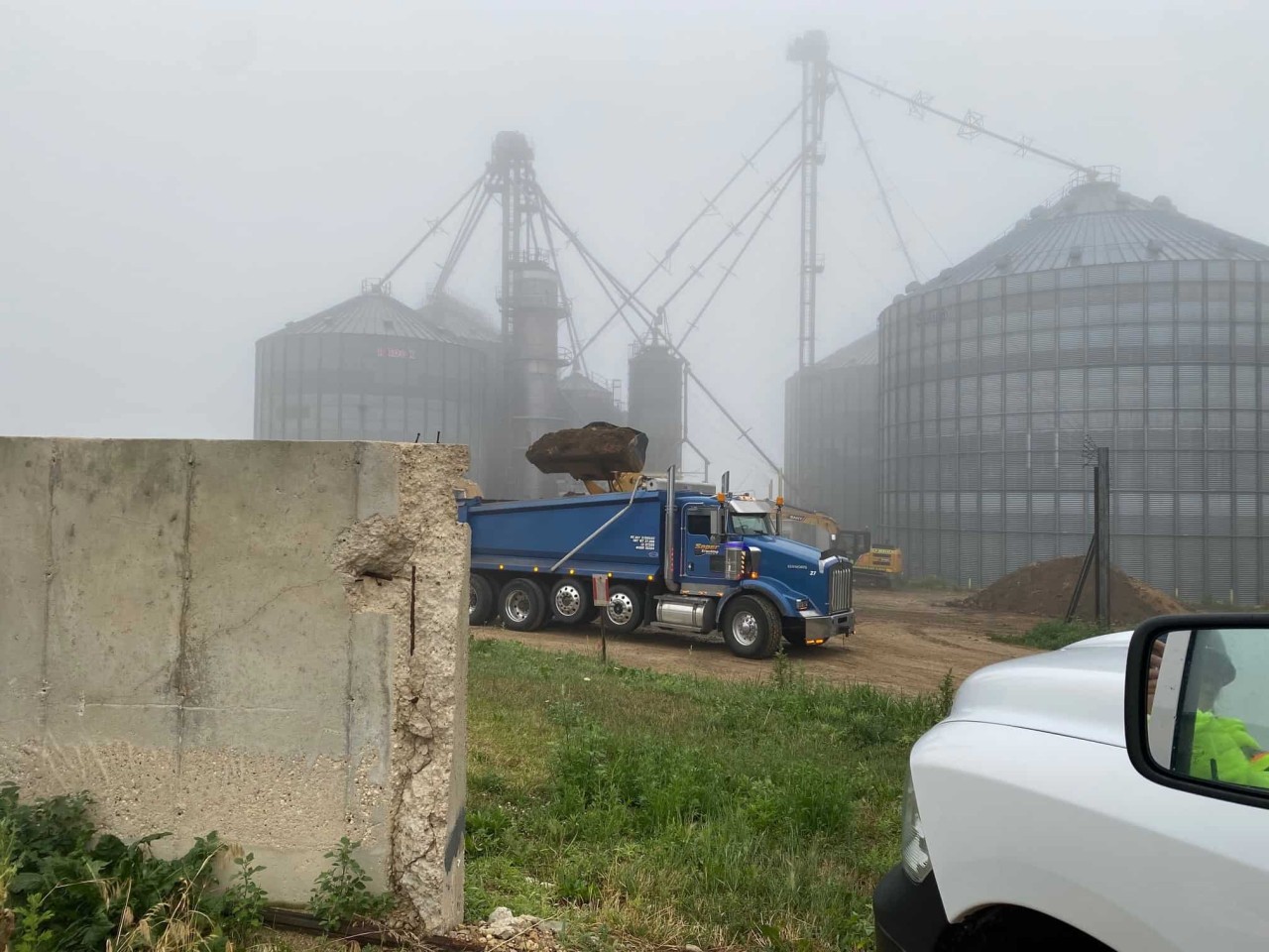 An excavator dumps contaminated soil at a landfill.